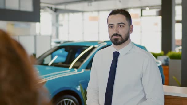 中东男性销售经理站在豪华轿车经销店前 与顾客夫妇谈论他们的要求 并将他们引开 — 图库视频影像
