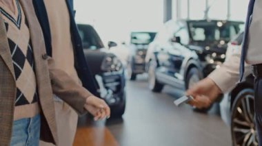 Tanımlanamayan erkek satış müdürünün, kadın müşteriye yeni arabanın elektronik anahtarını verirken ve adamla tokalaşırken çekilmiş yavaş çekimler.
