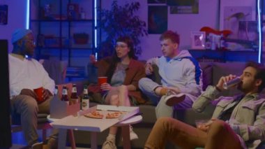 Orta boy beyaz bir kız, Afro-Amerikan ve Arap erkekler evlerinde kanepede oturup, pizza yiyip, bira içip, film ya da TV şovu izleyip, TV 'de olayları tartışıyorlar.