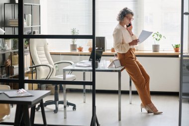 Olgun profesyonel denetçi ya da komisyoncunun sözleşme şartlarına ya da finansal belgelere bakıp cep telefonuyla konuşmasının yan görünümü