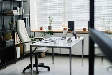 Masası ve merkezde duran rahat deri koltuğu olan şirket ya da işletme müdürünün geniş ofisinin içinde.