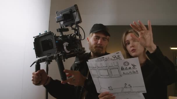 Genç Sarışın Yönetmenin Film Stüdyosunda Dikilirken Kameramanla Konuşurken Sahneleri Anlatırken — Stok video