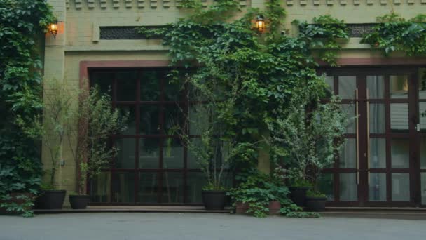 アイビーで装飾された大きな窓とガラスのドアを備えたモダンなクラシックスタイルのレストラン建物の外観のショットを確立 — ストック動画
