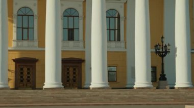 20. yüzyılın klasik stil tiyatrosunun beyaz sütunlu, ahşap kapılı, kemerli pencereli ve sarı duvarlı bir kısmını çeken insanlar yok.