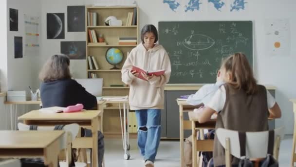 교실에서 책상에 괴롭히는 소녀는 바닥에 그녀의 드롭북을 만들고 다섯을하고 그녀를 — 비디오