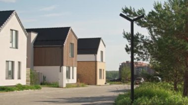 Güneşli bir yaz gününde şehrin varoşlarında asgari tasarım ile üç modern kır evinin çekimini yapmak