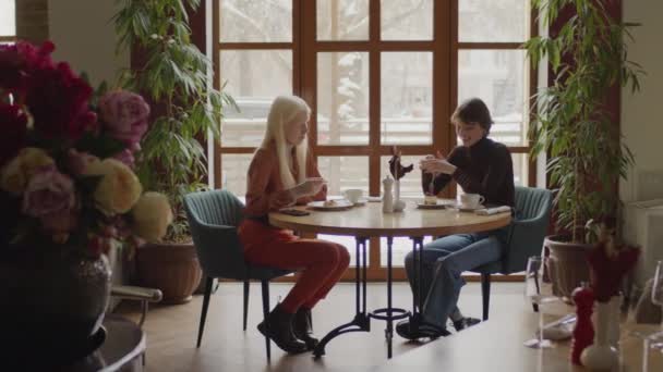 Két Sokszínű Fiatal Asztalnál Akik Desszertet Esznek Beszélgetnek — Stock videók