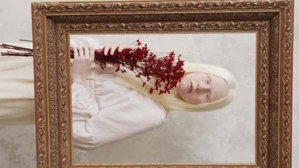 年轻白化病妇女拿着一束深红色的花看着相机的垂直画框工作室肖像 — 图库视频影像