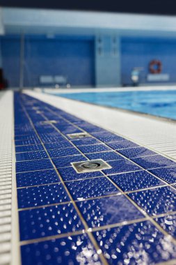 Spor antrenmanları ve müsabakalar için geniş yüzme havuzu boyunca mavi karolarla kaplı uzun havuz manzarası