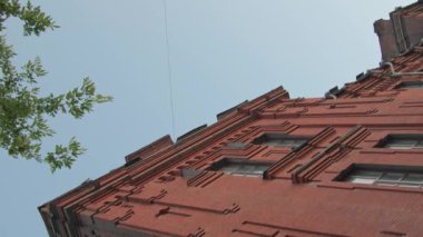 Yirminci yüzyılın kırmızı tuğlalı okul binasının dikey alçak açılı görüntüsü.