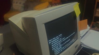 90 'ların garaj ofisindeki ekranda kod olan eski bilgisayar monitörünün orta ölçekli görüntüsü yok.