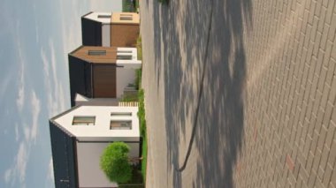 Yaz günü, küçük bir kasaba sokağında iki katlı, modern üç kulübeyi dikey eğimle çekiyoruz.