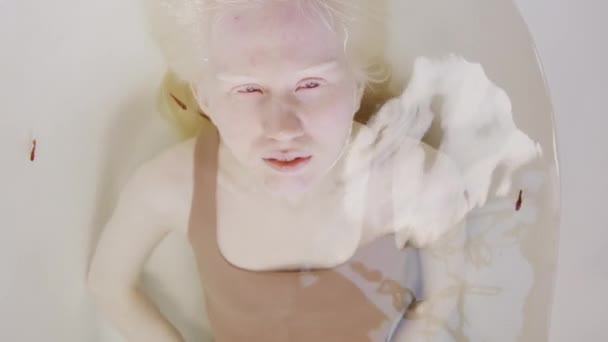 现代白化病女青年穿着棕色泳衣与鱼一起在浴缸里放松的自上而下的肖像 — 图库视频影像