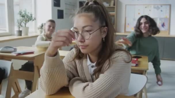 그녀에게 던지는 괴롭힘을 무시하려고 교실에서 책상에 우울한 소녀의 선택적인 — 비디오