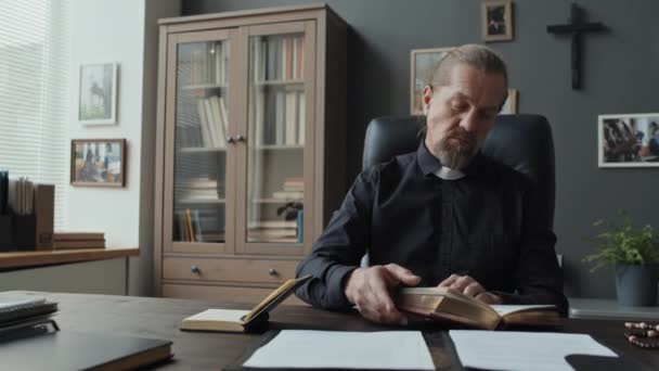 Middelgroot Portret Van Een Katholieke Priester Aan Een Houten Tafel — Stockvideo