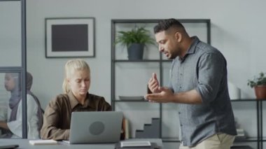 Orta boy, Orta Doğulu kaba bir adamın iş yerinde beyaz kadın astına kötü davrandığı bir fotoğraf.