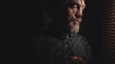 Orta boy yakın çekim, yetişkin Katolik rahibin günah çıkarma kabininde konuştuğu bir aşağı bir yukarı fotoğraf.