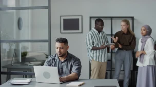 在办公室用笔记本电脑工作的中东人避免同事试图损害他的名誉的选择性镜头 — 图库视频影像