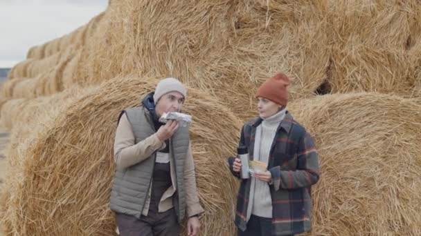 在寒冷的秋天里 男人和女人在农场外面站着与草垛作斗争 吃午饭 — 图库视频影像