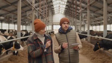 Çiftlikte çalışan kadın ve erkeğin planlarını tartışırken ve dijital tabletteki çizelgelere bakarken çekilmiş görüntüleri.