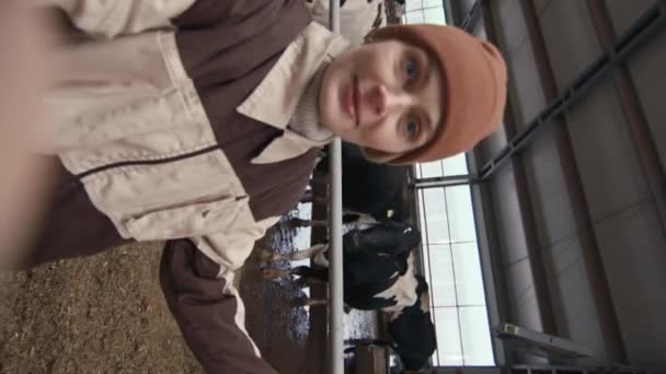 女性农民拿着摄像机为博客录像 向追随者展示奶牛的垂直照片 — 图库视频影像