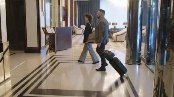 Длинный Снимок Пары Входящей Вестибюль Отеля Багажом Разговаривающей Друг Другом — стоковое видео