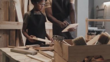 Babamın, marangozluk atölyesinde birlikte vakit geçirirken dijital tabletin planlarını oğluna gösterirken çekimini kaldır.