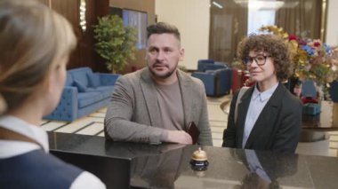 Bayan yöneticinin, konaklama yerleri ve pasaport alıp resepsiyona giriş yapmaları hakkında birkaç müşteriyle konuşurken omuz hizasında.