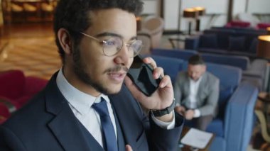 Meşgul girişimcinin otel lobisinde müşteriyle cep telefonu konuşmasını yakınlaştır