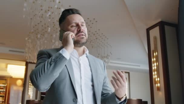 商人穿着西服站在酒店休息室时 用手机交谈的低视角 — 图库视频影像