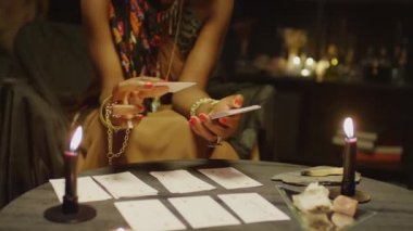 Falcının tarot kartlarını düşünmesi, planlama sırasında masada yanan mumlarla birlikte anlamına gelir.
