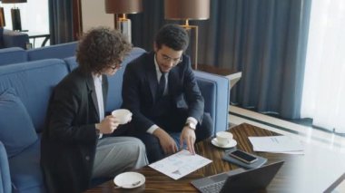 İş ortaklarının otel odasındaki kanepede otururken projeleri tartışıp belgelere baktıkları orta boy bir fotoğraf.