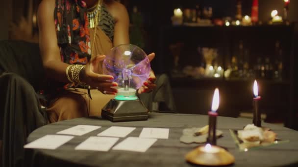 在她的工作室里 坐在桌子旁边 摆放着塔罗牌 点着蜡烛 手里拿着水晶球的透视手被剪下来的照片 — 图库视频影像