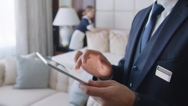 ホテルの管理者がデジタルタブレットの情報をチェックしながら 部屋でベッドリネンを構成する — ストック動画
