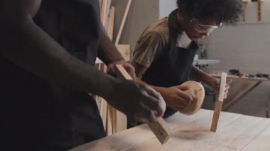Afro-Amerikan yetişkin bir adam ve oğlunun atölyelerinde birlikte kuş evi yaparken ahşaptan düz tahta yapmaları.