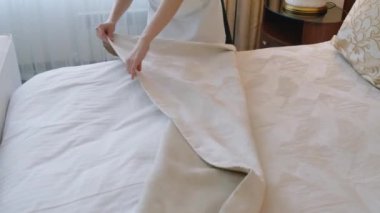 Otel odasında misafirler için yatak örtüsü hazırlarken çekilmiş bir fotoğraf.
