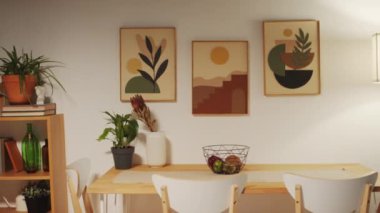 Masası ve aile yemekleri için sandalyeleri olan orta boy rahat bir yer, masanın üstünde retro posterler ve yanında düz bir lamba.