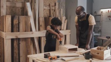 Afro-Amerikalı pozitif baba, marangozluk atölyesinde el işi yaparken oğluna beş dolar veriyor.