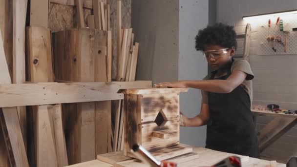 Афроамериканский Ребенок Полирует Вытирает Деревянный Скворечник Столе Одной Столярной Мастерской — стоковое видео