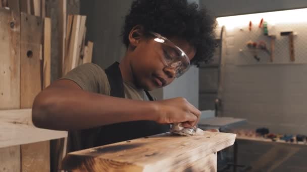 非洲裔美国男孩独自在木工车间工作时 在手工鸟舍屋顶上擦拭地面 — 图库视频影像