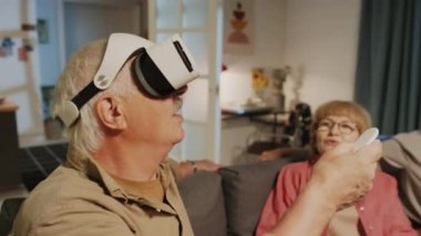 Oturma odasındaki kanepede arkadaşlarıyla otururken VR gözlüklerinin modunu değiştiren son sınıf öğrencisinin orta derecede yakın çekimi.