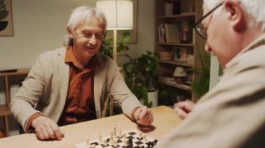 Akşam evde toplanırken satrançta birbirini kazanan neşeli adamların omuz üstü atışları.