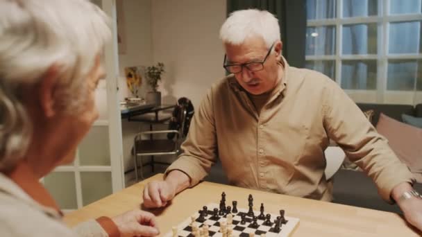 Över Axelbilden Koncentrerade Positiva Äldre Män Som Spelar Schack Hemma — Stockvideo