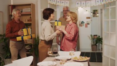 Orta yaşlı bir çiftin evde kutlama yaparken doğum günü kadınına hediyeler vermesi.