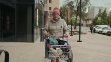 Islah evinde alışveriş arabasıyla gezen ve çöp kutularını karıştıran genç bir erkek.