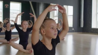 Taytlı küçük balerinler stüdyoda derse hazırlanırken ellerinin başının üstünde ısınıyorlar.