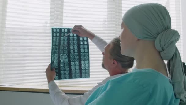 Через Плечо Зрелого Рентгенолога Объясняющего Молодой Женщине Результат Мрт Головного — стоковое видео