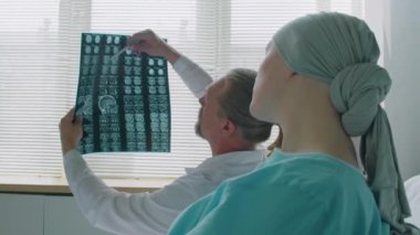 Hasta ve doktorun omuzlarının üzerinden hastane koğuşunda otururken beyin röntgeni taramasından bahsediyorlar.
