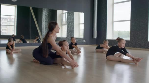 Jonge Leraar Helpen Groep Van Kleine Meisjes Doen Stretching Oefeningen — Stockvideo