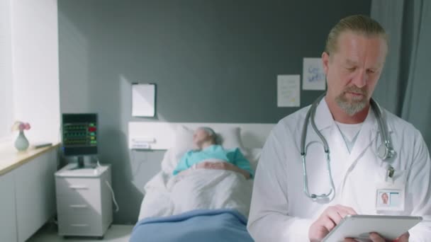 病気の患者と病気の病棟に立ってカメラを見ている成熟した医師の肖像画 — ストック動画